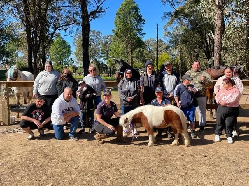 A group of participants and facilitators gathered with a miniature pony